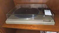 Front view of Pioneer PL-2 turntable with dust cover on wooden shelf.