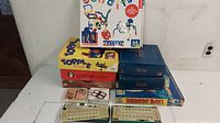 Photo showing stacked board games including Bendits, Topple, Scattergories, Yahtzee, Tornado Bowl, and bingo cards in front