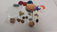 Overview of assorted pins including a miniature baseball and various lapel pins