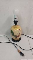 Full lamp view showing the painted rooster ceramic base, light bulb, and electrical cord.