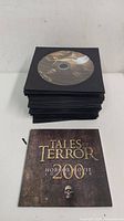 Stack of approximately 50 DVDs in black sleeves with one DVD showing a horror movie graphic and a cover DVD titled Tales of Terror 200 Horror Movie Collection with a skull graphic.