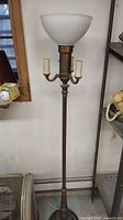 Full view of the tall antique brass floor lamp with frosted glass bowl shade and three candle bulb holders