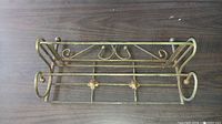 Top view of vintage brass hand towel rack showing side scrollwork and dual towel rods