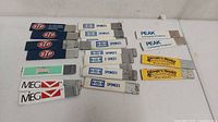 Photo showing fifteen assorted vintage promotional box cutters with logos including STP, O-Cel-O Sponges, Borax, MEG, Peak, and Lemon's Honey arranged on a white surface.