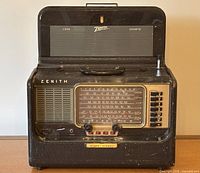 Front and top fold-out of antique Zenith Trans Oceanic Model B600 with visible tuning dial, push-buttons, speaker grill, and antenna extended.