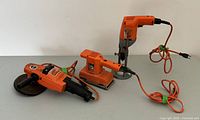 Photo showing all three Black & Decker power tools together: grinder polisher, dual action sander, and drill with stand.