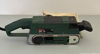 Side view of green Bosch PBS 75 Scintilla belt sander showing handle, sanding belt section, and adjustment knob