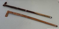 Pair of carved wooden canes laid side by side showing length and contrasting wood colors