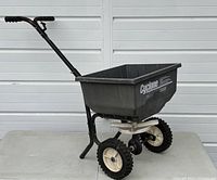 Side view showing entire spreader with hopper, wheels, and handlebar.