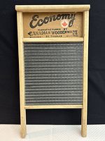 Front view of the Economy washboard with visible glass scrubbing surface and wooden frame, showing brand and manufacturing details on top wooden section.