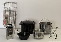 Full view of all items including black speckled canning pot with inside rack, two metal strainers, box grater, jelly/cheese strainers, canning tongues, and shredder.