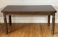 Dining table with leaves retracted, showing compact length and solid wood construction with turned legs.