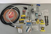 Top view of all miscellaneous handyman supplies including tubing, metal hooks, wire, screws, and hardware items arranged on a flat surface