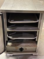 Front view with door open showing four removable stainless steel trays