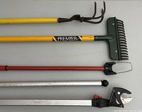 Photo of four long-handled garden tools laid flat showing rope and blade ends, informational labels and handle colors.