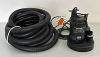 MasterCraft submersible sump pump with coiled 25 ft hose.