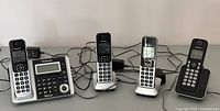 Full frontal view of the Panasonic phone system showing the base station and four wireless handsets with their charging bases all lined up on a flat surface.