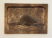 Full front view of carved wood panel featuring a beaver in a natural woodland setting with detailed trees and log.