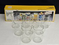 Nine clear SIMAK heat resistant glass cups arranged in 3x3 formation with original packaging box behind showing product details and branding