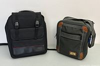 Front view of black Targus computer backpack and green travel tote standing side by side on a white surface