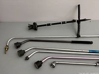 Set of one telescopic gutter cleaner and five sprinkler wands laid out on a surface.