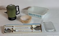 Full lot showing four items: green thermos, small peach Fire-King bowl, Pyrex Butterprint baking dish with ribbed lid, and salad serving set in box.