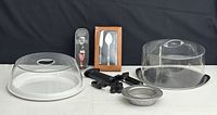 Photo of entire lot showing cake domes, wine bottle holder, serving utensils, aerating pourer box, and wine air pumps
