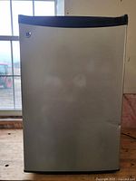 Exterior closed view of the compact fridge showing stainless steel door with black trims.