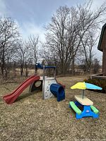 Slide and picnic table shown side by side on grass yard