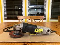 Side view of Stanley FatMax angle grinder showing logo, grip, and attached grinding disc.