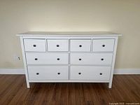 Front view of white wooden dresser with four small drawers on top row and four larger drawers below