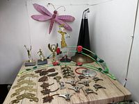 Wide view of all metal items laid out on wooden surface including sculptures and decorative pieces