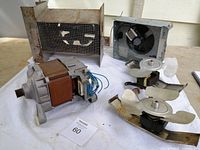 Image showing one metal box fan assembly with mesh, two small axial fans with white plastic blades, and one electric motor with copper windings and attached wires laid out on white background.
