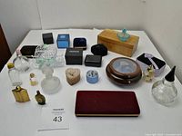 Full view of a collection of various jewellery boxes, miniature bottles, and decorative items arranged on a white surface.