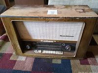 Front view of large vintage Normande radio showing wood casing with wear, speaker fabric, control panel with knobs and buttons