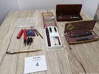Lot overview showing multiple fountain pens, boxes, ink cartridges and accessories on table.