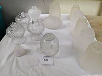Overview of 13 vintage glass lampshades including frosted half moon, milk white hobnail textured, ribbed clear or milk white, and additional frosted shapes on white cloth background.
