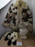 Full view of vintage patchwork suede girl jacket with fur trim, real fur hat on mannequin head, and rabbit fur neck warmer laid on table