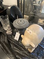 Five Asian decorative items displayed on black cloth: two elephants, glass vase, Buddha statue, and black ornamental piece.