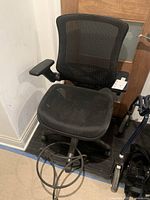 Photo showing black mesh office chair with armrest and adjustable features