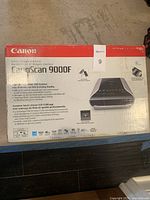 Front view of the Canon CanoScan 9000F box showing product name, resolution, and feature highlights.