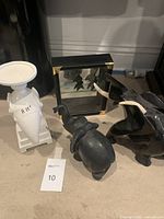 Photo showing white ceramic candle holder, stone and ceramic elephants, and wooden display box with miniature elephants