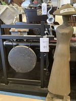 Photo showing the 20x24 inch gong mounted in a black wood and metal frame, in front of various items.