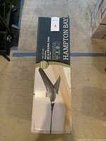 Photo of the sealed box for Hampton Bay 60 inch black industrial ceiling fan, showing the product image and brand name.