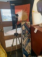 Full view of Manfrotto tripod, Logan Mat Cutter box, and Asian floral fabric art hanging in front of door