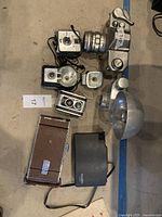 Overview of vintage camera collection showing Polaroid 450, Kodak Duaflex, brown Polaroid camera, and assorted flashes and accessories.