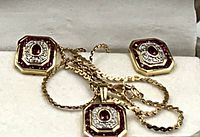 Octagonal pendant and earrings laid on soft cloth, chain partially arranged