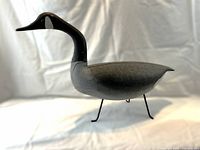Right-side profile view of carved goose decoy on tripod legs