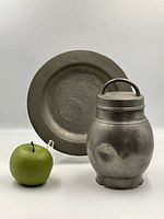 Photo showing both the antique pewter plate and lidded jar side by side with a green apple for scale.