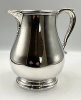 Front view of English Georgian style sterling silver pitcher, showing body and base